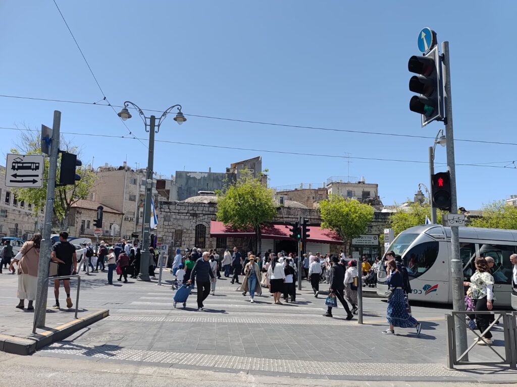 עוברים ושבים חוצים את הכביש ליד תחנת כיכר ציון בירושלים, יום אחרי חג העצמאות 2025