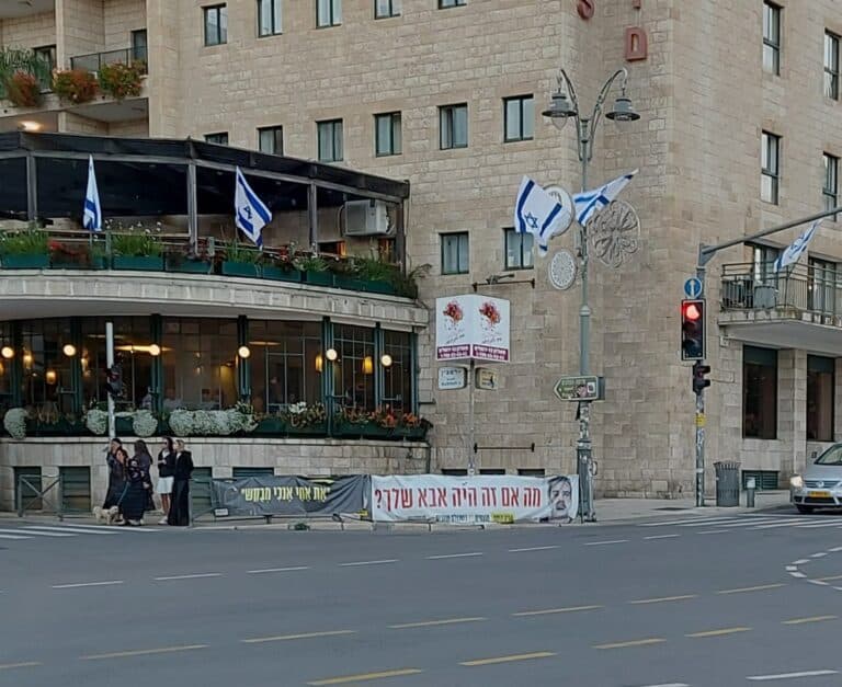 רחוב ירושלמי עם מדרכות עמוסות, סימני עומס ותנועה כבדה – אווירת שגרה צפופה לאחר חג הפסח