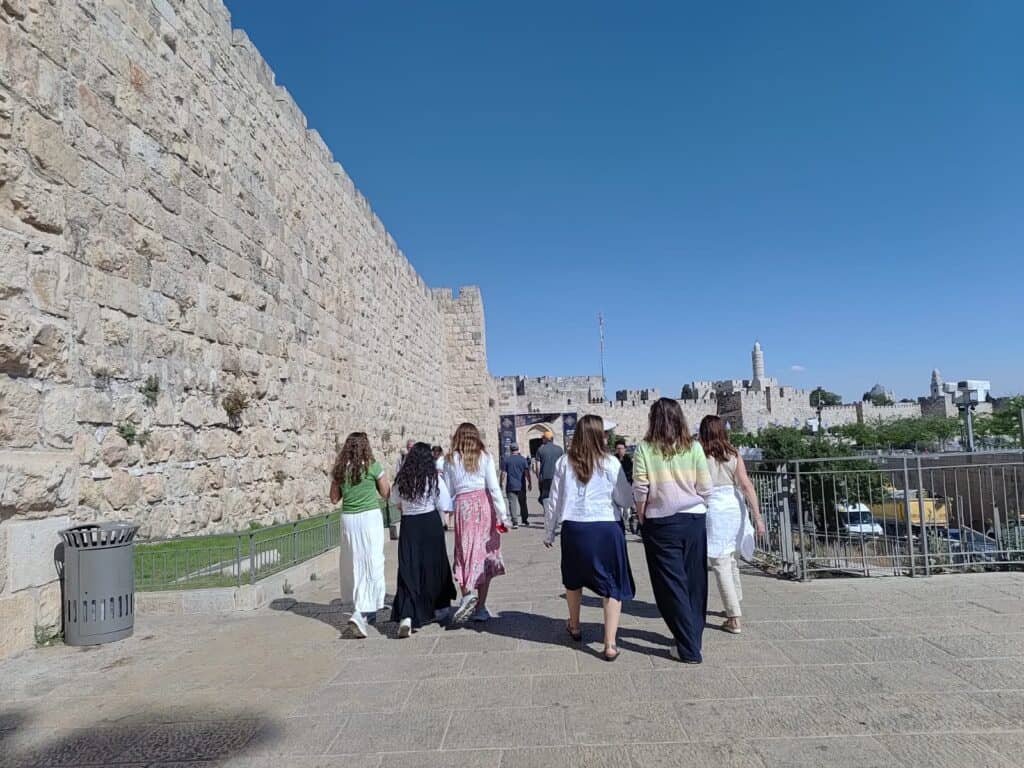 Women walking toward the Old City walls of Jerusalem on a sunny day – symbolizing a spiritual journey to the Western Wall during transit disruptions