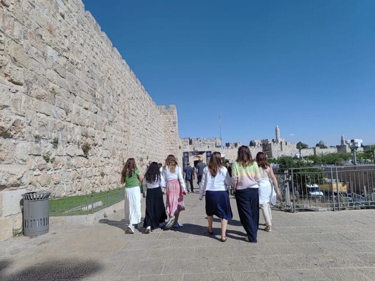 Women walking toward the Old City walls of Jerusalem on a sunny day – symbolizing a spiritual journey to the Western Wall during transit disruptions