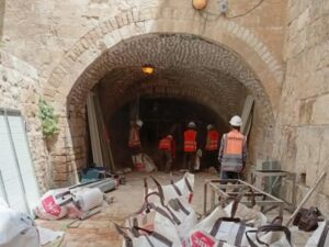 עבודות שיפוץ ותחזוקה בכותל הקטן בירושלים, פועלים ואנשי צוות בתוך קשת אבן עתיקה, הממחישה את נושא הכתבה