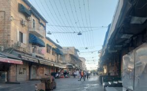 שוק מחנה יהודה בירושלים ביום בהיר, ממחיש את חיי היומיום בעיר לקראת מזג האוויר הצפוי