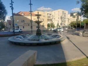מזרקה וסביבתה בכיכר פריז בירושלים. נקודת מפגש עירונית תוססת המשקפת את חיי היומיום והפסיפס האנושי של העיר