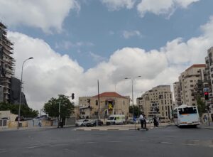 רחוב בירושלים עם בניין הנושא סמל סרט צהוב, המשקף את הדופק והאווירה העירונית.