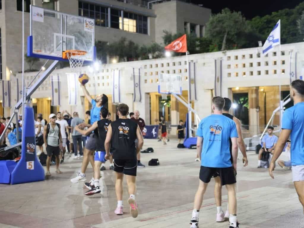 Basketball street tournament in Jerusalem's Safra Square, players in mid-game, July 2025