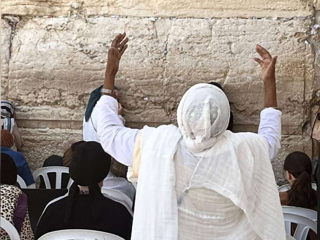 A woman prays at the Western Wall in Jerusalem ahead of Tisha B’Av, raising her arms in deep emotion