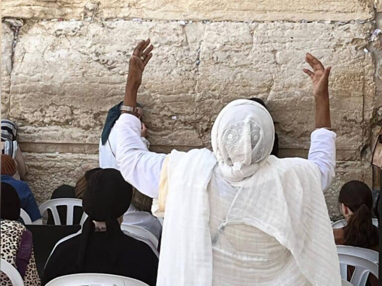 A woman prays at the Western Wall in Jerusalem ahead of Tisha B’Av, raising her arms in deep emotion