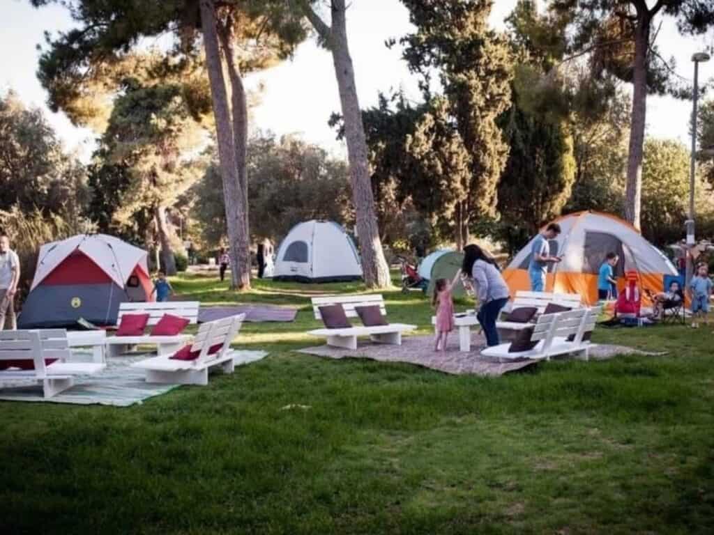 Tents and families gathered in a Jerusalem neighborhood park during a community camping night am