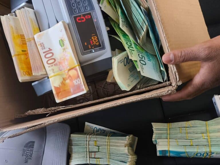 Bundles of Israeli currency and weapons seized during a police fraud investigation in Jerusalem he