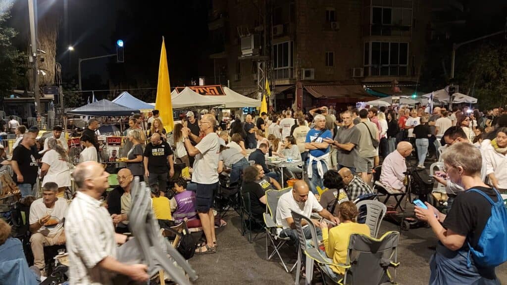 משפחות ותומכים במאהל מחאה ברחוב עזה בירושלים בערב ראש השנה, אוכלים ארוחת חג עצובה על הכביש