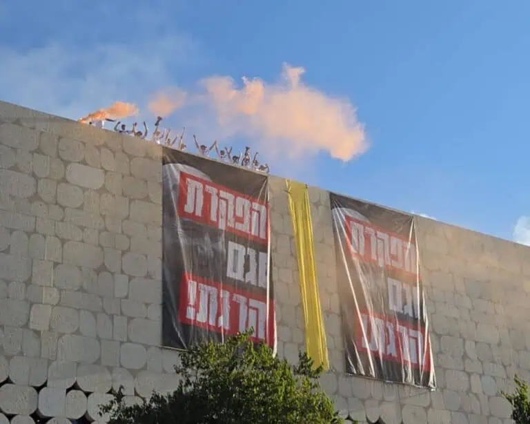 Penunjuk perasaan dengan sepanduk dan bom asap di bumbung bangunan di Givat Ram semasa protes tebusan di Baitulmaqdis