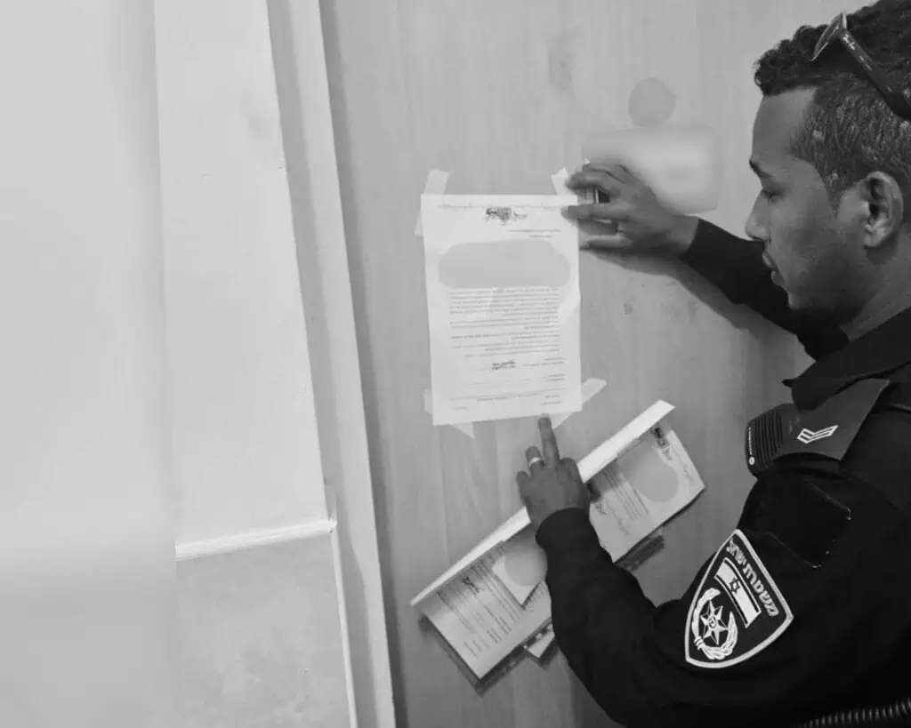 Pegawai Polis Daerah Baitulmaqdis menampal perintah penutupan pada sebuah apartmen di Beit Shemesh selepas menggaji penduduk tanpa izin