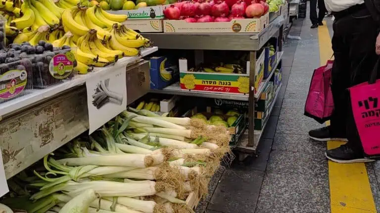 Gerai sayur dan buah di pasar Mahane Yehuda Baitulmaqdis dengan daun bawang, delima dan epal