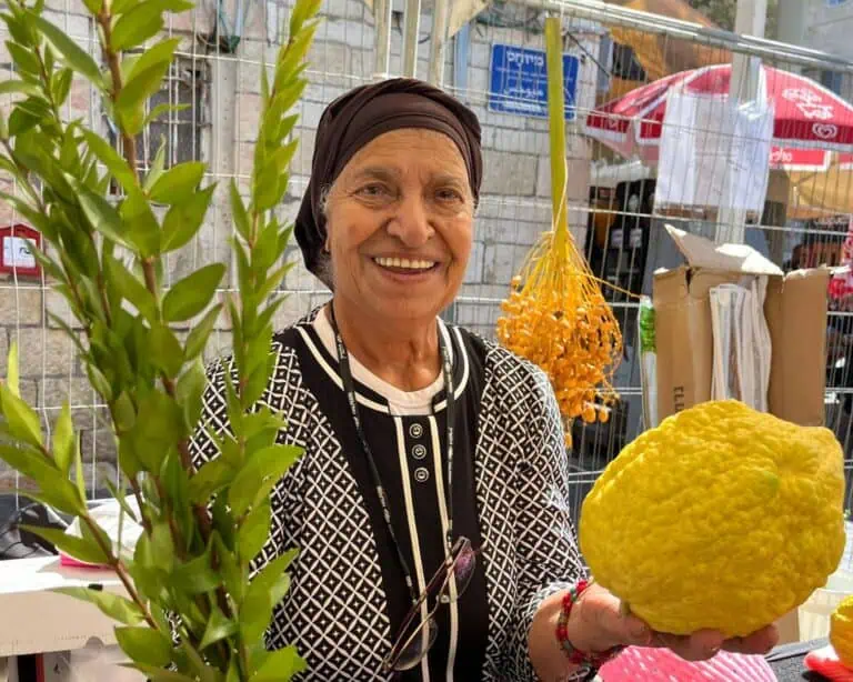 Seorang wanita memegang etrog dan lulav di Pasar Sukkot Baitulmaqdis